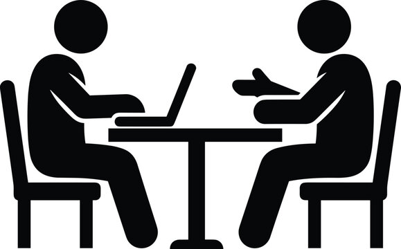 Two people sitting at a table with a laptop and one person gesturing meeting discussion computer