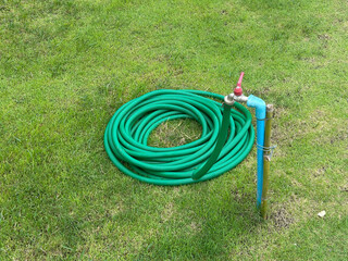 Rubber hose with water tap for watering in park.