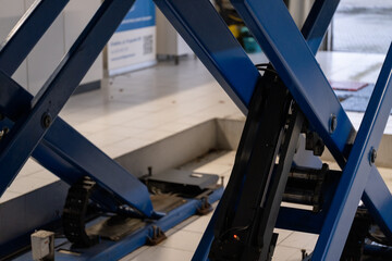 Naklejka premium Hydraulic car lift platform in modern auto service workshop
