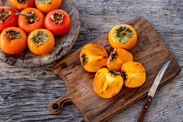Fototapeta premium Ripe persimmon fruits in the wooden bowl. Trabzon or cennet hurması 