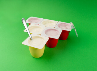 Yogurt cups set, pink and yellow fruit yoghurt in plastic pots, milk pudding container with spoon