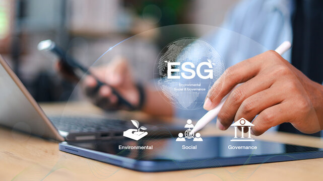 Businessman using tablet and smartphone with ESG icon overlay. Concept of sustainable business, environmental responsibility, social impact, and good corporate governance in digital era.