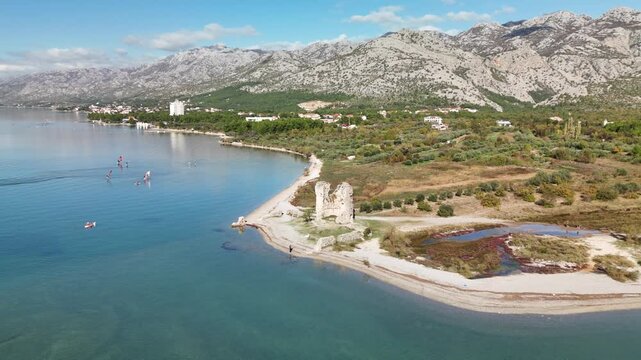Drone footage circles Večka kula, a 16th‑century Venetian fortress in Starigrad Paklenica, framed by Velebit mountains and the sparkling Adriatic Sea, showcasing Croatia&rsquo;s coastal heritage and beauty.