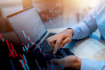 A man is using a laptop and pointing at a screen with a red and green line