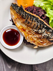 Delicious steamed mackerel with soy sauce on black rice, topped with sesame and served with lettuce and carrot. Healthy homemade Asian food concept.