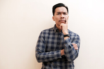Obraz premium Southeast Asian man wearing flannel shirt thinking about something while looking to upper right corner, on white isolated background