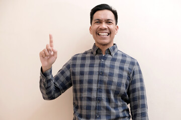 Fototapeta premium Southeast Asian man wearing flannel shirt showing happy excited expression with giving number 12345 by hand gesture, on white isolated background.