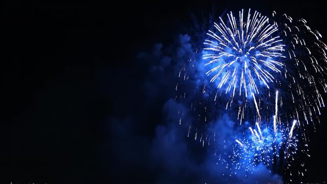 Bright blue fireworks explode against the night sky. Vertical pyrotechnic display for a celebration. Holiday event with copy space