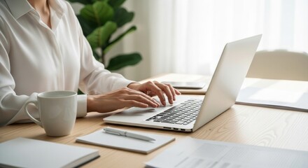 Person Working on Laptop at Modern Desk with Coffee and Documents