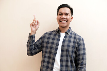 Southeast Asian man wearing flannel shirt cheerful expression pointing to the right side with excited expression, on white isolated background