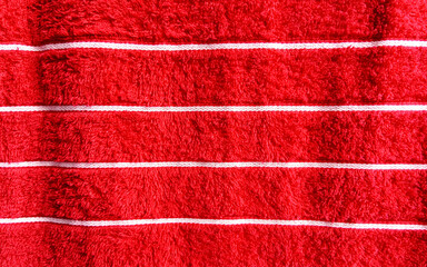 Close-up of red towel fabric with white horizontal stripes and soft terry texture. Perfect for textile design, hygiene product mockups, or clean fabric backgrounds.