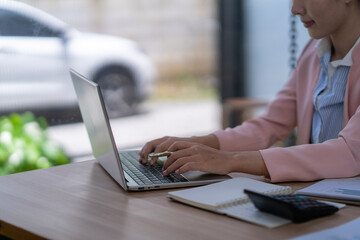 Businesswoman working on laptop with financial reports and calculator in office