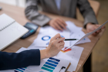 Businesswomen analyzing financial charts and data at office desk