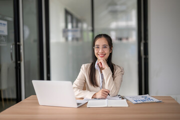 Fototapeta premium Young asian businesswoman smiling and working on laptop in office meeting room