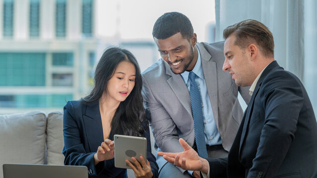 diverse group business professionals sitting on couch looking tablet. business teamwork brainstorm colleague meeting discussion strategy urban office smart working