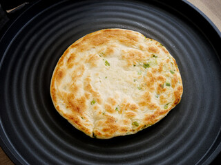 Handmade Scallion Pancake Pan-Fried in Black Skillet - Delicious Golden Asian Flatbread with Green Onions