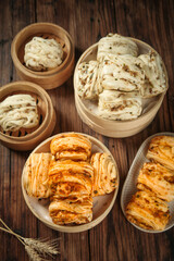 Handmade Asian Steamed Buns and Savory Pastries in Bamboo Steamers on Wooden Table