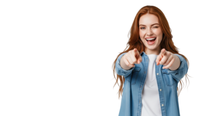 Joyful young caucasian woman with vibrant red hair, denim and white t-shirt, laughing, winking, and pointing at viewer in a bright studio with plain light grey background. Concept of positive