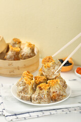 Traditional Chinese Siu Mai Dumplings with Meat and Egg Yolk Served with Chopsticks