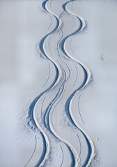  Aerial winter mountain slope with fresh ski and snowboard tracks creating graphic S curves in pristine snow 