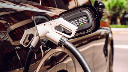 Charging an electric vehicle at a station on a sunny day in the city