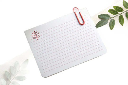 White blank rectangular note paper with a red paperclip on the corner 