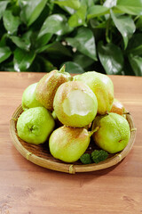 Fresh Whole Korla Pears from Xinjiang China in Traditional Bamboo Basket on Wooden Table