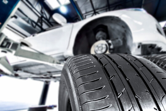 New tire treads ready for installation under a car on a lift. Auto repair, car service, and tire replacement