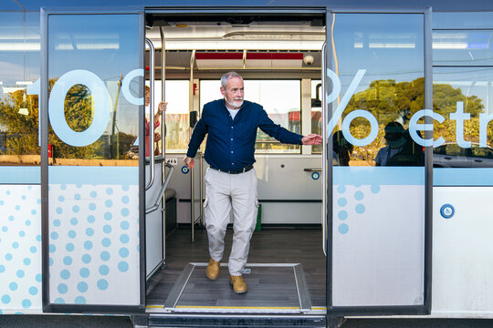 Senior man stepping out of a city bus door, riding public transport in an urban environment. Travel, accessibility, and modern living