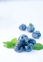 Fresh blueberries of natural color with green leaves on a white background. Forest wet berry close-up