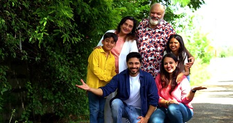 Indian family standing together outdoors looking at camera, smiling and bonding happily in nature, multi-generation portrait of grandparents, parents, and children enjoying weekend time - Powered by Adobe