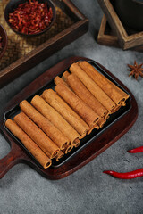 Long Natural Cinnamon Sticks from Guangxi China with Traditional Spices and Chili Peppers in Wooden Tray