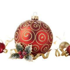 A festive red Christmas bauble adorned with glittering gold swirls and holly berries sits on a dark background with scattered golden ribbons and small red baubles hinting at a holiday celebration