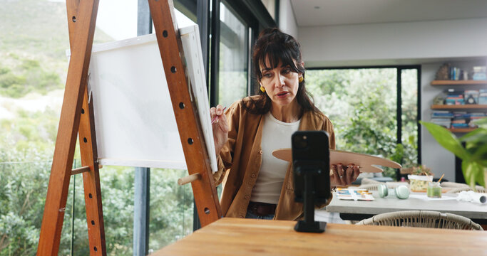 Home, painter and woman with smartphone, influencer and live streaming with fans engagement. Online app, artist or mature person with canvas, cellphone or content creation with tips or showcase craft