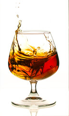 A glass of liquor with ice cubes in it is splashing water out of it