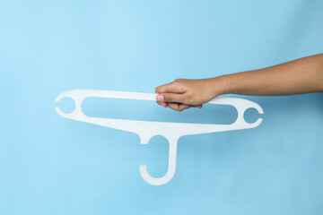 A woman's hand is holding a plastic white hanger on an isolated background