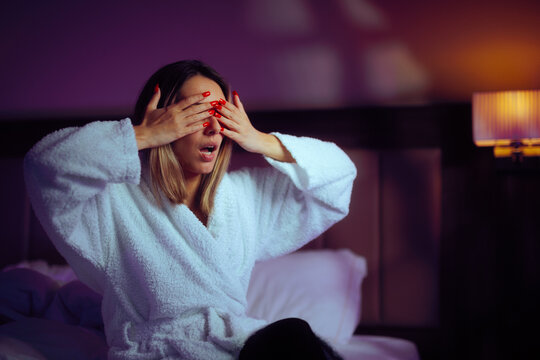 Woman Covering her Eyes Being Surprised in a Hotel Room. Girlfriend waiting in bed for her surprise to arrive 
