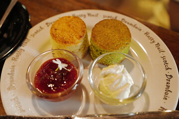 Close up Matcha green tea scone served with clotted curd cream and strawberry jam
