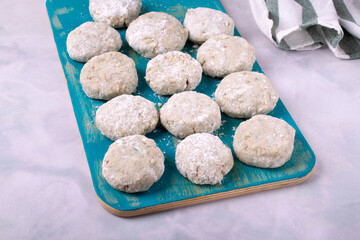 Cooking haddock fish cakes made of mince on blue cutting board. Shaping the patties