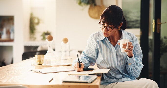 Woman, writing and notebook with coffee in home for planning, finance reminder and payment timeline. Mature person, beverage and notes for household budget, tracking expenses and financial management