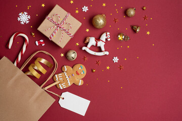Christmas shopping composition concept with paper bag and gifts on red background