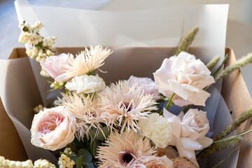 Mixed flower bouquet with roses, gerberas, and berries, carefully placed inside a cardboard delivery box, ready for gift giving
