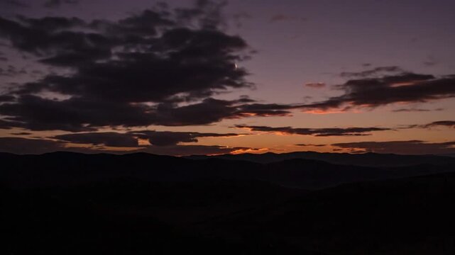 Beautiful sunset over rolling hills with dramatic clouds painting the sky in vibrant colors