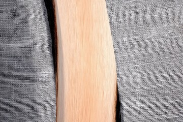 A light-colored wood plank with a natural, uneven live edge is placed on a textured gray fabric background.