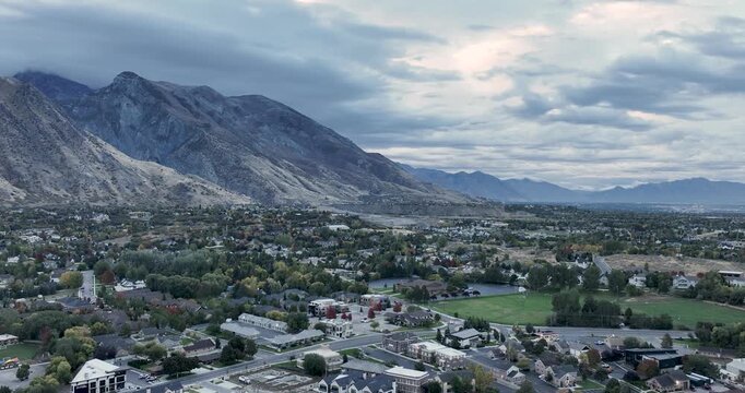 Stunning aerial footage of American Fork, Utah, showcasing the picturesque valley below the Wasatch Front. The captivating landscape includes lush greenery and dramatic mountain ranges in Autumn