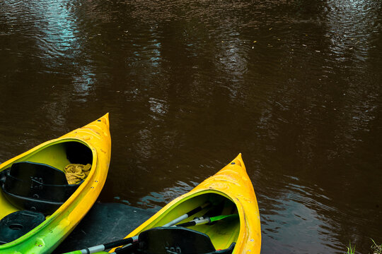 two yellow kayaks on river bank - ready for rent