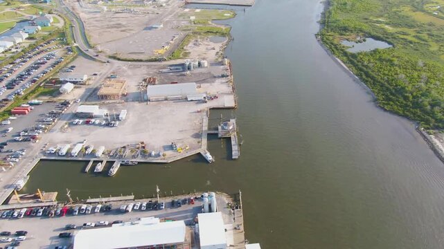 Drone flies over Bayou Fifi toward the Grand Isle Marina, capturing views of Fifi Island, full parking lots, waterfront construction, and the bustling coastal event center.