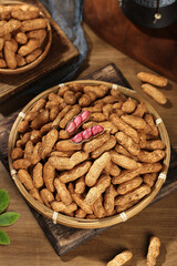 Fresh Red Coated Peanuts in Shell with Wet Coating in Wicker Baskets on Wooden Background
