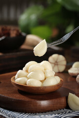 Fresh Shandong garlic cloves in wooden bowl with fork - peeled white garlic bulb heads for cooking