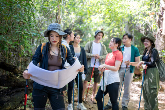 Group of friends exploring forest trail using map - Powered by Adobe